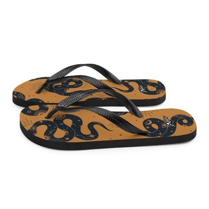 JERGHATS flip-flops with a tan base, black snake and celestial print, and black Y-shaped rubber straps.